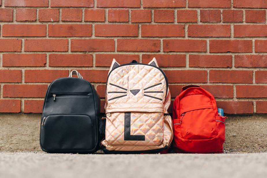 three-childrens-backpacks-along-brick-wall_925x